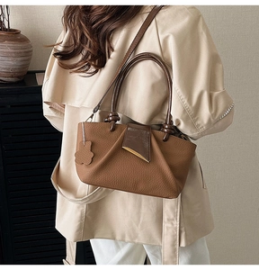 Detail of lychee textured leather handbag with pleated design and bear charm