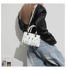 Detail of white leather motorcycle bag with silver rivets and studs on a model