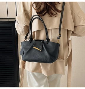 Black pebbled leather trapezoid handbag with gold hardware and stylish ring handles
