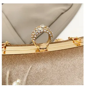 Detail of velvet evening clutch featuring a gold metal frame and rhinestone ring buckle