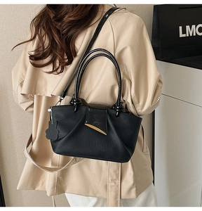 Detail of black pleated leather tote bag with gold metal clasp and floral bag charm