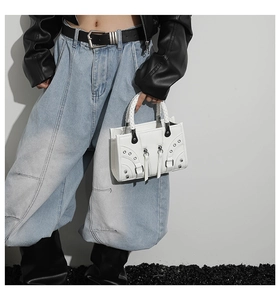 Detail of white biker bag with silver rivets and woven leather handle in edgy style