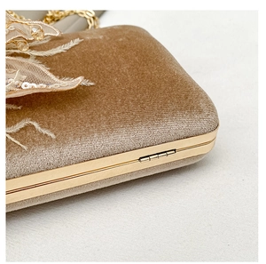 Detailed close-up of champagne velvet evening bag with gold metal frame and sequins