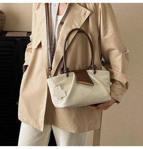 Close-up of textured leather handbag with brown handles and gold metal hardware trim