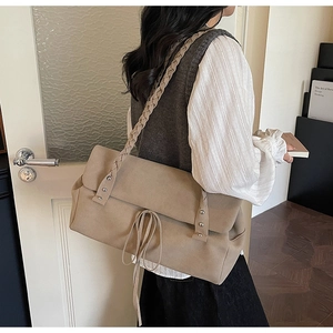 Detail of beige frosted suede shoulder bag with woven strap and metallic rivets
