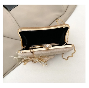 Detail of champagne gold evening clutch featuring rhinestone clasp and pearl feather tassels
