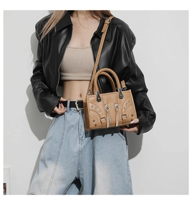 Detail of light brown punk style leather handbag with metallic silver eyelets and studs