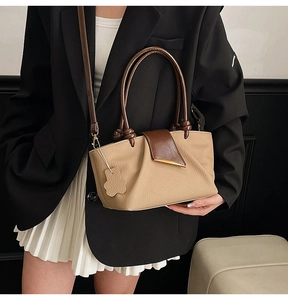 Detail of a two-tone hobo bag with teddy bear charm and elegant twisted top handle