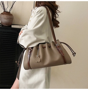 Detail of a brown lychee pattern leather shoulder bag with a stylish drawstring design
