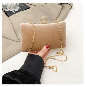 Close-up of champagne gold velvet evening clutch featuring a sparkling rhinestone ring clasp