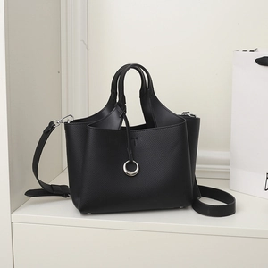 Detail of black pebbled leather tote bag with silver ring charm and adjustable strap