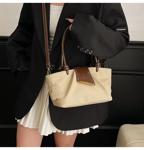 Close-up of pleated leather detail and gold buckle on beige and brown handbag