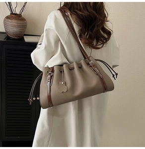 Detail of taupe pebbled leather tote bag with drawstring closure and brown handles