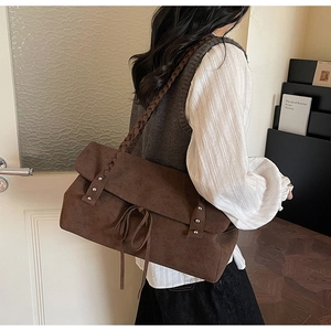 Detail of dark brown suede tote bag with woven shoulder strap and metal rivets decoration