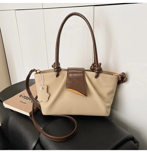 Detail view of beige lychee leather tote with brown knotted handles and crescent metal buckle