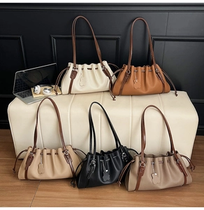 Detail view of five colors of pleated tote bags featuring drawstring closure and leather charms
