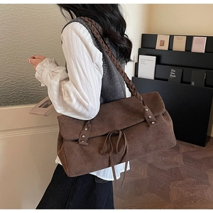Brown faux suede tote bag featuring braided straps and silver rivet details on model