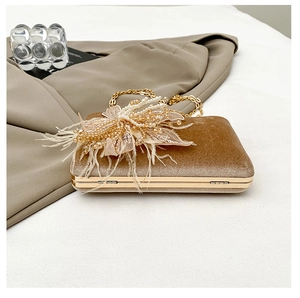 Detail of tan velvet clutch featuring handcrafted pearls and delicate feather flowers