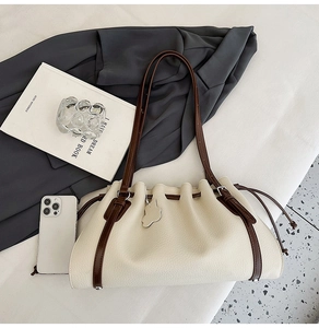 Close-up of a cream drawstring bucket bag with lychee grain texture and brown straps