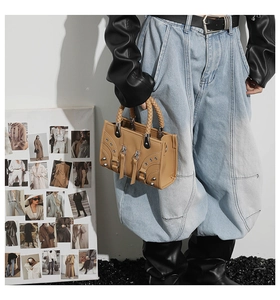 Detail of camel leather handbag with silver punk rivets and woven handle on a model