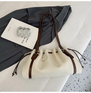 Close-up of pebble leather bucket bag with drawstring closure and silver cat charm detail