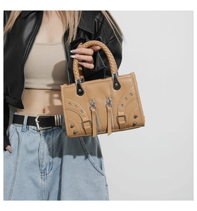 Detailed close-up of camel faux leather handbag featuring woven handle and metallic rivets