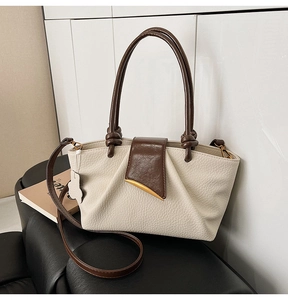Detail of beige lychee textured tote bag with contrast brown handle and gold crescent buckle