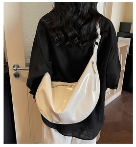 Detailed side view of a large white crescent bag on model showing style and capacity