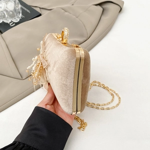 Close-up of champagne velvet clutch with diamond lock, pearls and gold chain