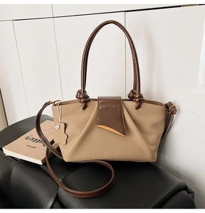 Close-up of two-tone leather handbag with knotted handles and gold half-moon hardware