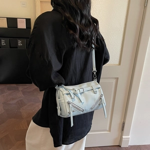 Light blue PU leather pillow bag with silver zippers shown on a shoulder in daily setting