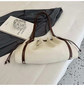 Detail of drawstring pleated opening and lychee grain leather on off-white shoulder bag
