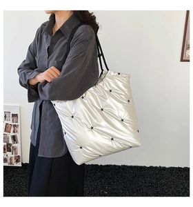 Detail of silver quilted tote bag with black star embroidery and thin shoulder straps