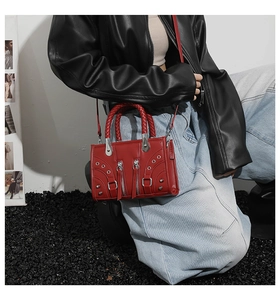 Detail of red motorcycle handbag showing metallic zippers, rivets, and woven handles