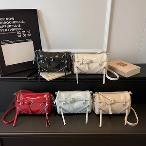Glossy patent leather baguette bags in five colors displayed on a modern podium