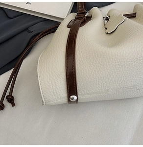Detail of lychee pattern leather bucket bag with silver rivets and drawstring