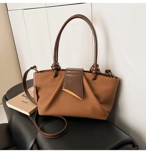 Close-up of brown lychee-textured leather handbag with golden hardware and buckle detail