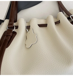 Detailed view of cream bucket bag with lychee grain texture and brown drawstring