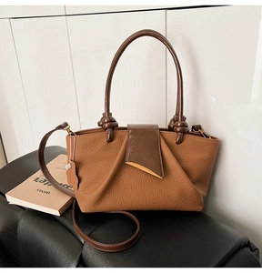 Detail of brown litchi leather handbag with unique triangular clasp and knotted handle