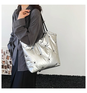Detail of silver metallic quilted tote bag with black star pattern and sleek shoulder straps