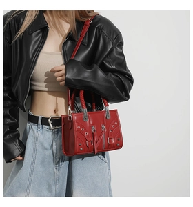 Detail of red punk motorcycle bag featuring silver rivets and textured leather texture