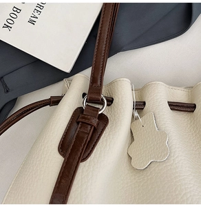 Detail of lychee textured cream bucket bag with drawstring and floral leather charm