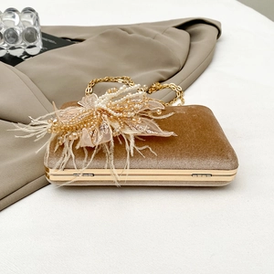 Detail of luxury brown velvet evening bag with pearls, sequins and feather decoration