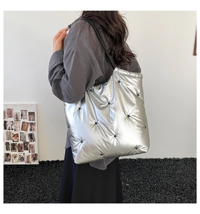 Side view of silver puffer tote bag with black star embroidery on model for daily commute
