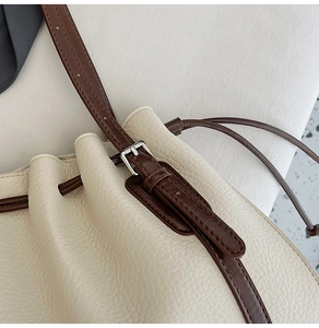 Detail of beige lychee textured leather bucket bag with silver buckle and drawstring