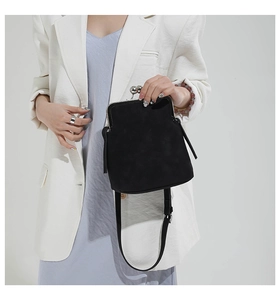 Detail of vintage black shell bag with silver ball clasp on model in white blazer