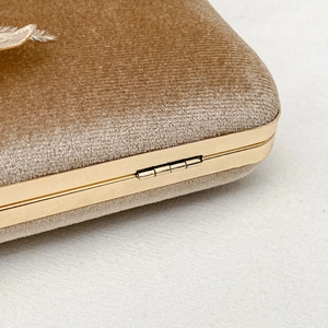 Detailed macro view of khaki velvet handbag with gold metal hinge and fine lace edges