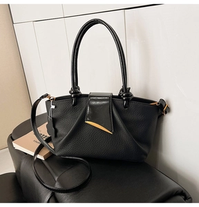 Close-up of black lychee-textured leather handbag with golden metal hardware and twin handles