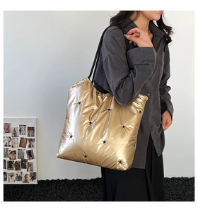Close-up of golden metallic quilted tote bag with black star embroidery on model