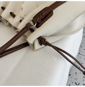 Detail of white lychee leather texture and contrast drawstring on shoulder bucket bag